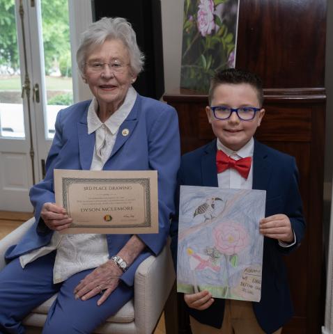 Dyson McLemore is shown with Alabama Governor Kay Ivey and his “2026 Governor’s Mansion Art Contest” winning entry, while Ivey holds his official certificate.
