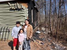 Karen Marchan and children Derek, 10, and Leah, 7, stand in front of their home, which burned in a fire last Tuesday.